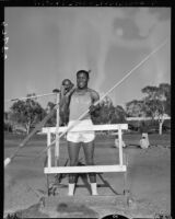 Rafer Johnson poses with track and field equipment.