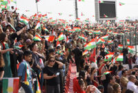 People in the stands cheering and holding Kurdish flags