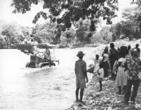 Italian artist, Gian Cassone, crossing a rushing river upon return from an ISPAN inventory of Fort Riviere, North Haiti