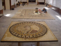 Conserved Berenike mosaic in forefront with member of project staff working on stag hunt mosaic in background