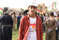 A young man wearing a white shirt and cap with a motto, " Yes for Kurdistan Independence"
