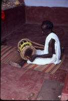 Mannān Velayudhan playing an izhārā hourglass drum at the home of Chummar Choondal, Chettupuzha (India), 1984
