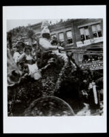 Carriage with an African American coach driver and four young white women in a floral parade float, 1890-1910