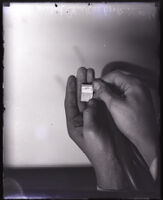 Hands holding the world's smallest book, Los Angeles, circa 1920s