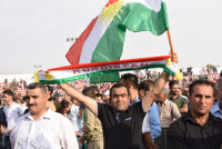 A man holding Kurdish flags