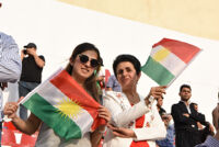 Two women holding Kurdish flags