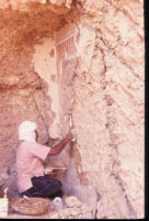 Mohammed ‘Abd el-Warris filling rock wall surface at south end of rekhyt frieze with mud plaster. View looking south.