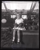 A young girl holding two large avocados, Orange County, 1928