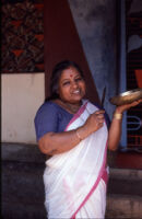 Thankamma Brahmani Amma holds a bronze bowl and knife striker used when she sings Brahmani Pattu songs, Avinissery (India), 1984