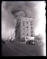 Firefighters on ladder fighting fire on 5th floor of Newmark Bros. building, Los Angeles, 1928