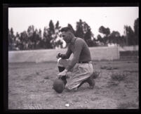 Football player and coach Albert Andrew Exendine holds the football in place to be kicked, Los Angeles, 1920-1929