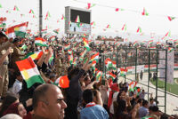 People cheering on the stands and waving Kurdish flags