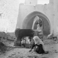 Village women roasting grains in a stone oven
