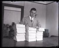 Judge Samuel R. Blake holding a pen over three stacks of transcripts, Los Angeles, 1926