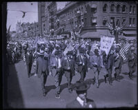 Parade on street with men holding small American flags, Los Angeles County, 1920s