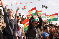 People cheering and holding Kurdish flags