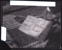 Armenian Bible displayed on a rug and held open by Philip H. Kazanjian, Los Angeles, circa 1928