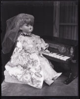 Doll with glasses, positioned to play a toy piano, Los Angeles, circa 1920s