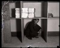 Harry Adler crouches under a shelf, Los Angeles, circa 1927-1931