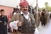 A man wearing Kurdish military clothing holding a rifle