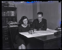 Commander Richard E. Byrd seated next to a woman pointing at a map on a desk, Los Angeles, 1920s