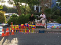 Two men selling food and drinks in front of Sulaimani Stadium