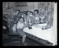 Loretta Turnbull, international outboard motorboat champion, in bed with her trophies, Monrovia, 1931