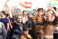 A family wearing Kurdish clothing and holding Kurdish flags