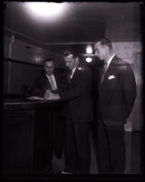 David H. Clark and two unidentified men standing at a front desk, Los Angeles, 1931