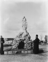 Snapshot of two priests in front of Saint Vincent de Paul's statue