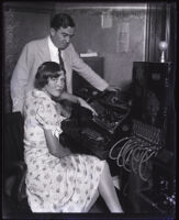 Sheriff Eugene Biscailuz standing next to a woman at a switchboard, Los Angeles, circa 1930s
