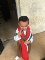 Voting in Khanaqin, A young boy wearing Kurdish clothing, flag of Kurdistan around his neck, and lifting an inked finger