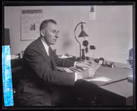 Buron Fitts seated at a desk in his office, Los Angeles, 1928