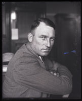 John R. Quinn sits backwards on a chair with arms cross over the back, California, circa 1923
