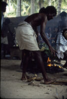 Villupāttu event - man stokes a fire for a manjal nirattam trance ritual at the Ayyappan Temple, Achankulam (India : Village), 1984