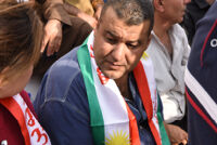 A man with a Kurdish flag around his neck.