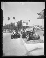 Police officer Stanley Elkins beside wrecked car which is used as a warning to reckless drivers in Hermosa Beach, Calif., 1948