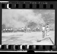 Group of children on bicycles watching grass fire in Baldwin Hills, Calif., 1972