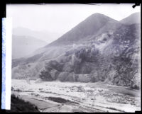 Cloud of dust and debris cascading down San Gabriel Canyon wall after explosion during dam construction, 1929