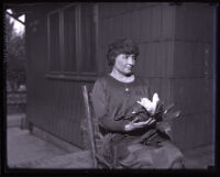 Helen Keller sitting holding a magnolia flower, Los Angeles, circa 1920