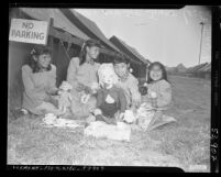 Four American Indian girls playing with dolls and tea set at a tent city in Calif., circa 1951