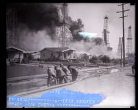Firefighters laying hoses to protect homes from oil well fires, Santa Fe Springs, 1938