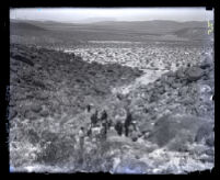 Birds-eye view of sheriffs and search team looking over rocky terrain at Sugarloaf Canyon, San Diego County, Calif., 1920