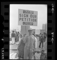 Demonstrators at "economic survival" rally, one holding sign reading "Draft Ralph Nader for President" in Los Angeles, Calif., 1974