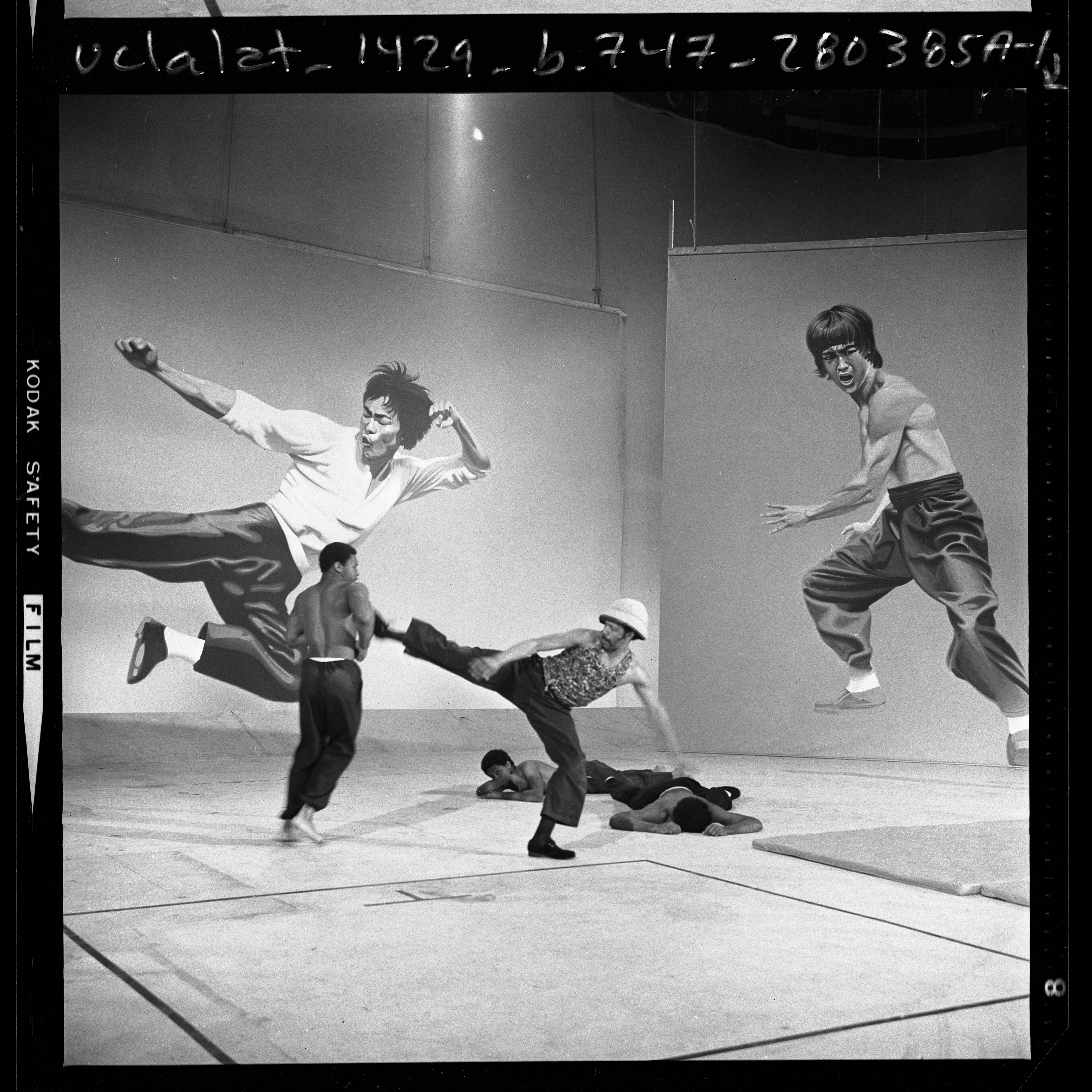 Image of four men performing karate before backdrops with images of Bruce Lee during audition