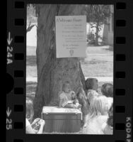 Toddler, Yvette Heltom seated beneath sign reading "A Woman's Right:.." at abortion rights event in North Hollywood, Calif., 1975