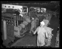 Men loading bags of flour on trucks at loading docks of Los Angeles Globe Grain & Milling Co., circa 1939