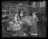 Aimee Semple McPherson and Mrs. M. B. Godbey in a pantry preparing Christmas food baskets, circa 1935