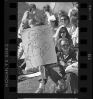 Bob Coutts holding sign with cartoon reading "This pocket is empty! LA Board of Education" at rally in Los Angeles, 1987