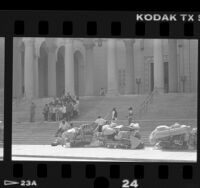 Homeless men watch as group of people have picture taken on steps of Los Angeles City Hall, Calif., 1988